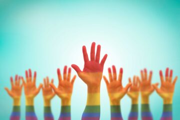 Raised hands painted in rainbow colors