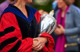 robed faculty member holding university mace