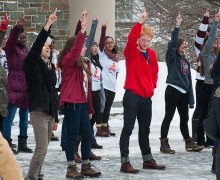 Students in a flash mob on the Quad all show the number 1 with their fingers
