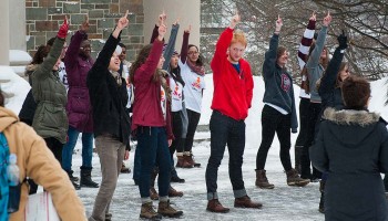 Students in a flash mob on the Quad all show the number 1 with their fingers