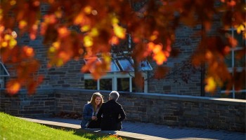 Student speaks with family member framed by autumn leaves