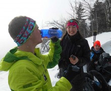 Student in snow gear drinks from a Colgate water bottle among friends