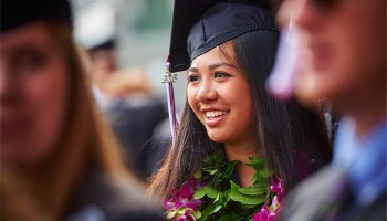 Student with flowery leis in graduation garb