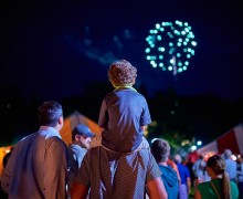 Child watches fireworks from his father's shoulders amid the reunion tents