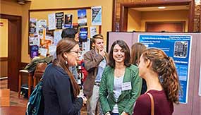 Students chat with alumni at poster presentation