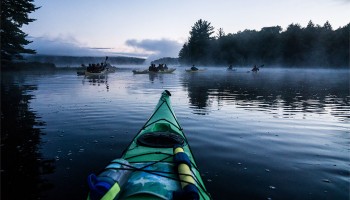 Students kayak through the morning mist on Cranberry Lake in the Adirondacks
