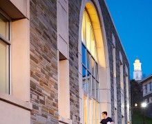 Student enters Case Library with Memorial Chapel at dusk visible in the background