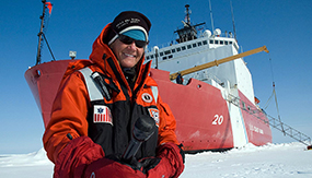 Elizabeth Arnold ’82 standing on ice in front of a ship