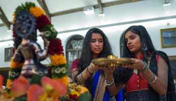 Two students in traditional attire hold a gold plate in the Hall of Presidents during Diwali, the Hindu festival of lights.