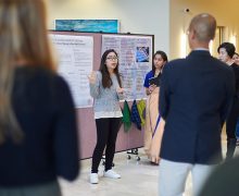 A Lampert Institute fellow presents a research poster to a gathered crowd.
