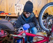 Student performs maintenance on the chain of an upturned bicycle
