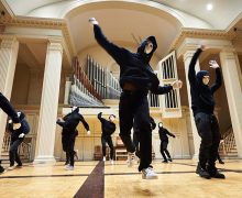 Student dancers dressed in black and wearing white masks on stage at Colgate Memorial Chapel.