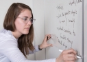 Woman in glasses writing on a whiteboard