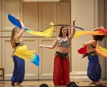 Students perform with the Bellydancing club at Dancefest, as two students twirl with scarves, a third balances a sword on her head