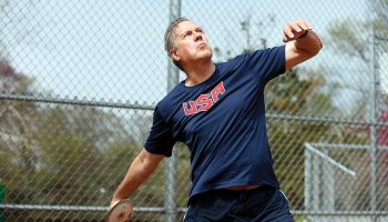 Roger Busch ’63 in a USA shirt throwing a discus