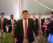 Student sings a solo with his a capella group under the lights in a tent