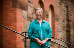 Portrait of Marilyn Thie, professor of philosophy, religion, and women’s studies, on the steps of Hascall Hall