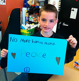Martin Richard holding a sign that reads "No more hurting people: Peace"