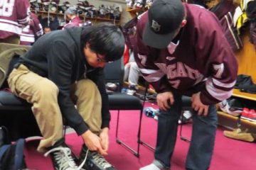 Ryan Johnston '16 helps a Colgate student put his skates on prior to hitting the ice.
