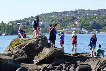 Students climb on a rocky outcrop near the water