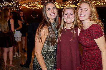 Three students stand together smiling in the Hall of Presidents during the Colgate Lymphoma Gala