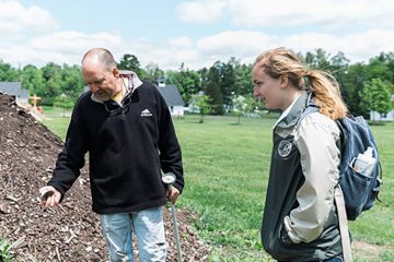 Grace Thomas ’17 stands with Bob Sutherland in a field at Mohican Farms.