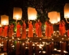 Monks in orange robes prepare lanterns near a body of water