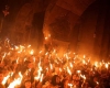 A tightly packed crowd marches with torches at night