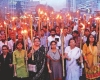 A crowd of men and women stands with torches