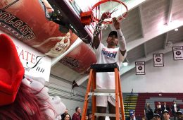 Jordan Burns ’22 cuts down the net as he celebrates Colgate's first Patriot League Men's Basketball title in 23 years.
