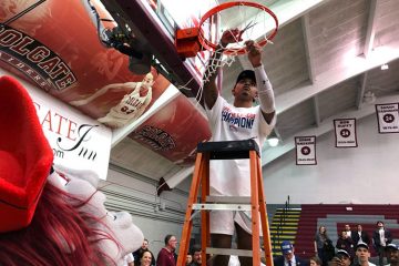 Jordan Burns ’22 cuts down the net as he celebrates Colgate's first Patriot League Men's Basketball title in 23 years.